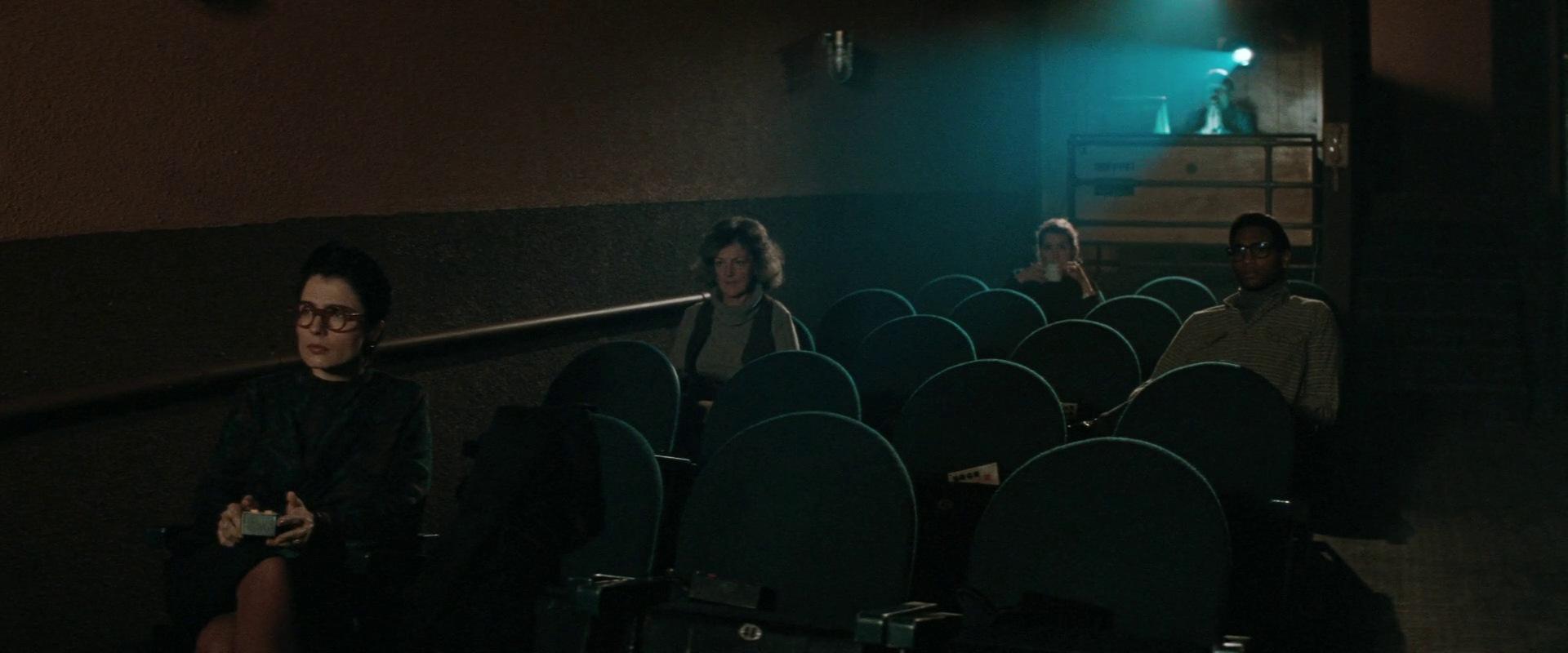 Several people sit in a dark movie theater