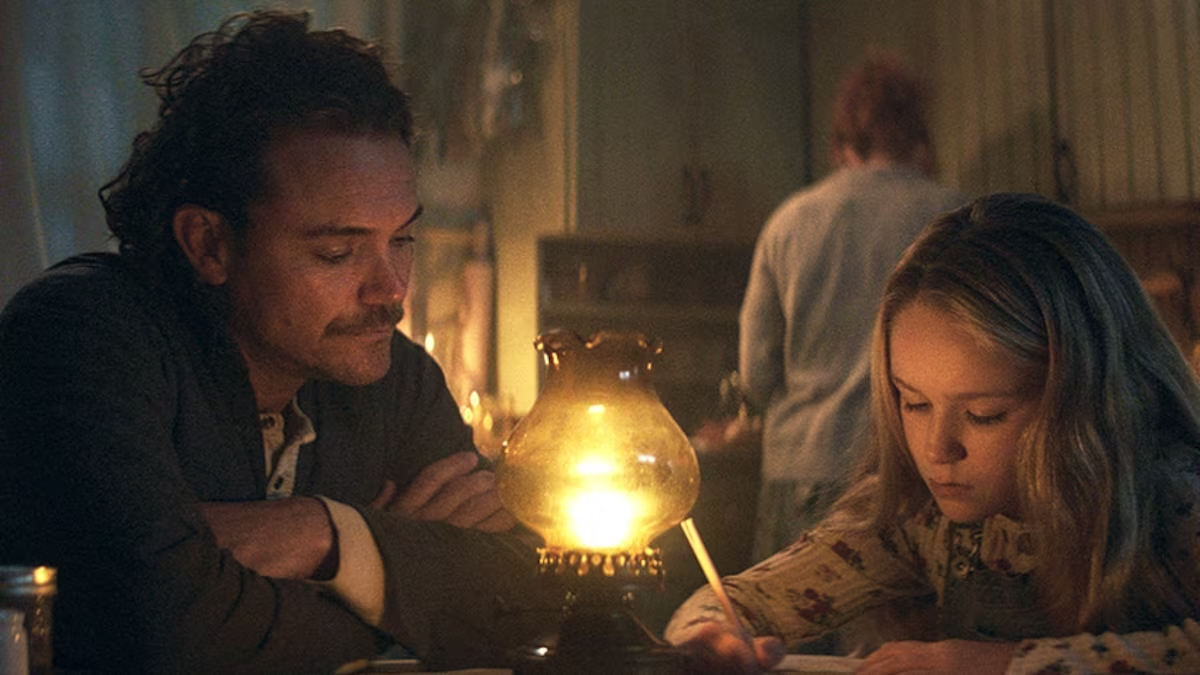 Bobby (Clayne Crawford) watches adopted daughter Isla (Alix West Lefler) write in candlelight