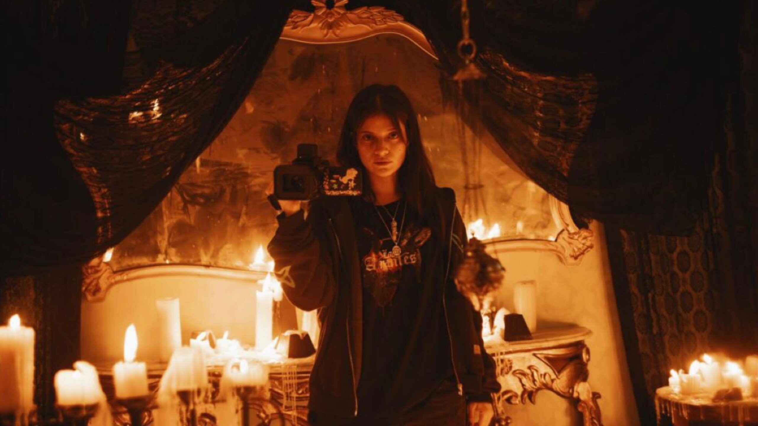 No Me Sigas review - woman holding up camera in dark room lit by candles