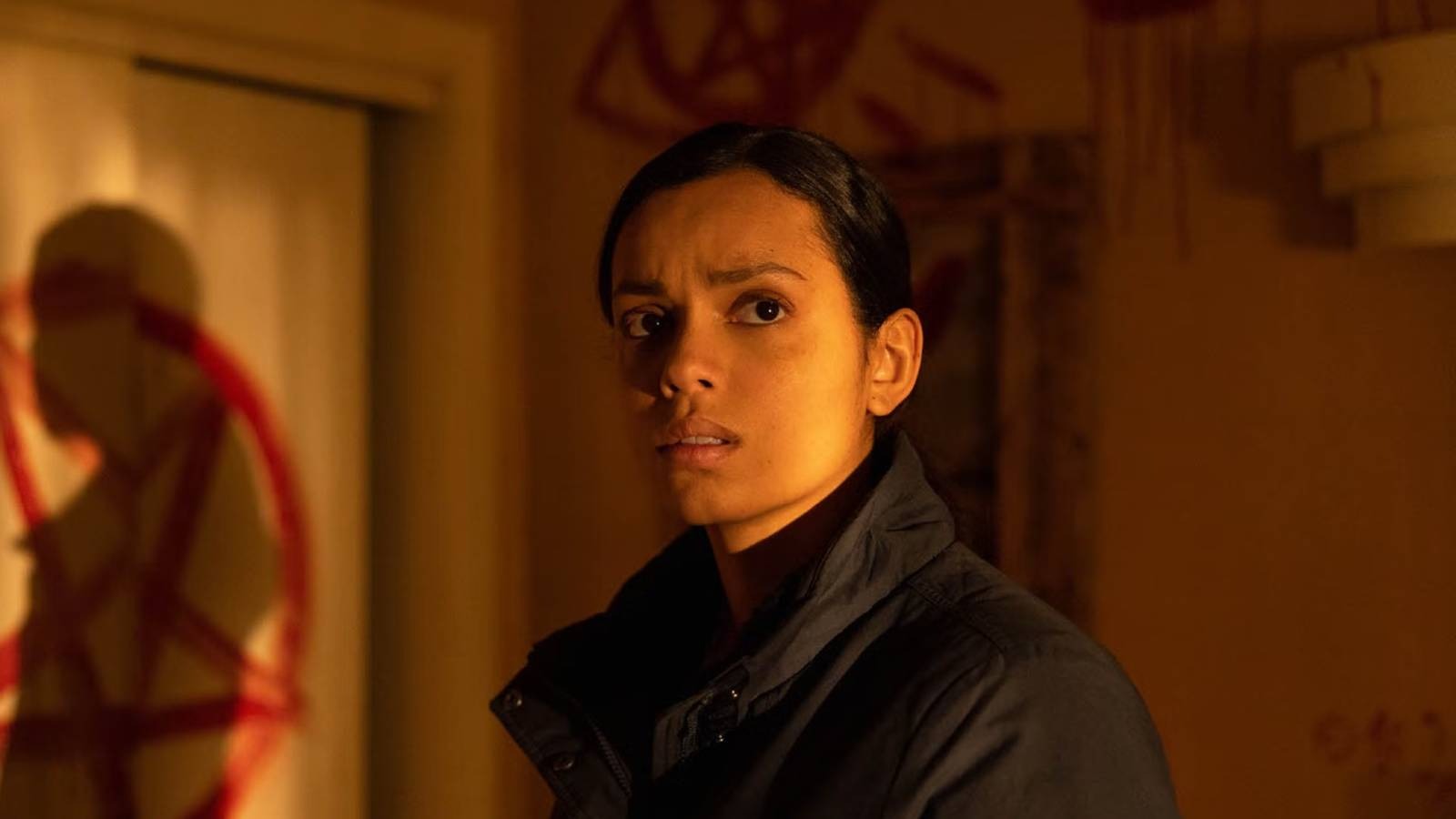 Horror Scream Queen Georgina Campbell stands in front of door with painted red pentagram in Psycho Killer still